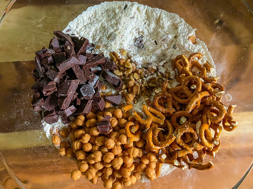 caramel bits, pretzel pieces, chocolate pieces, and chopped walnuts in bowl of flour mixture