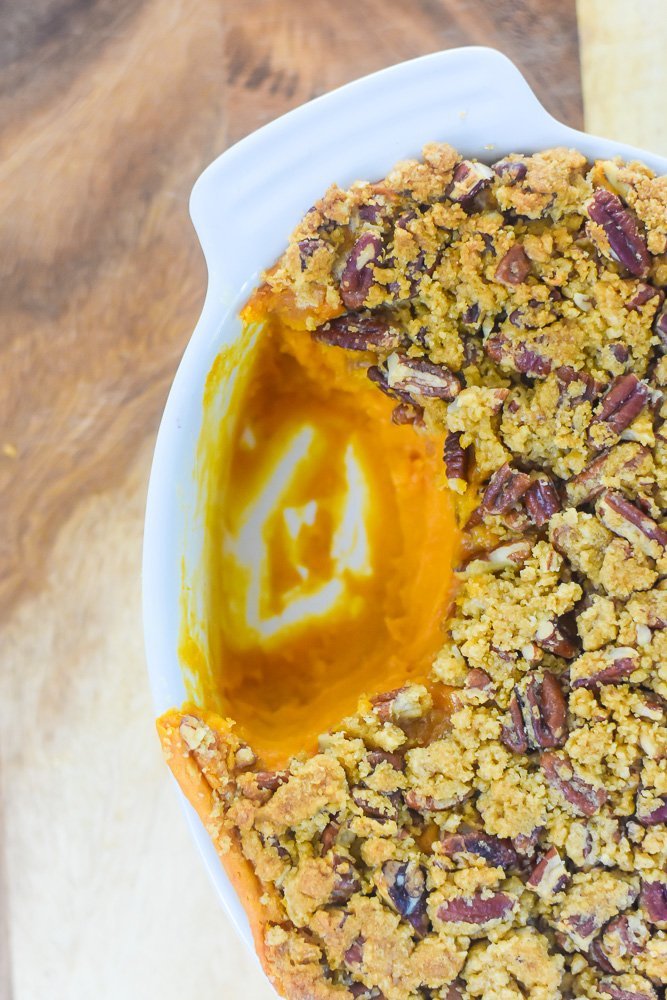 The best bourbon sweet potato casserole with crunchy streusel topping served out of a white casserole dish.