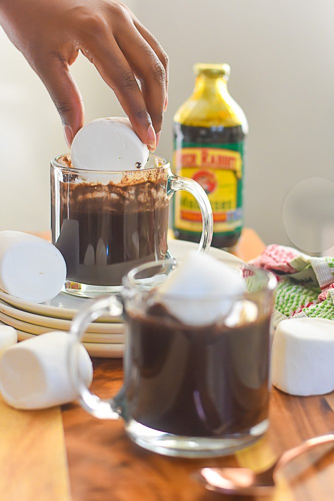 placing jumbo marshmallow in mug of bourbon gingerbread hot cocoa