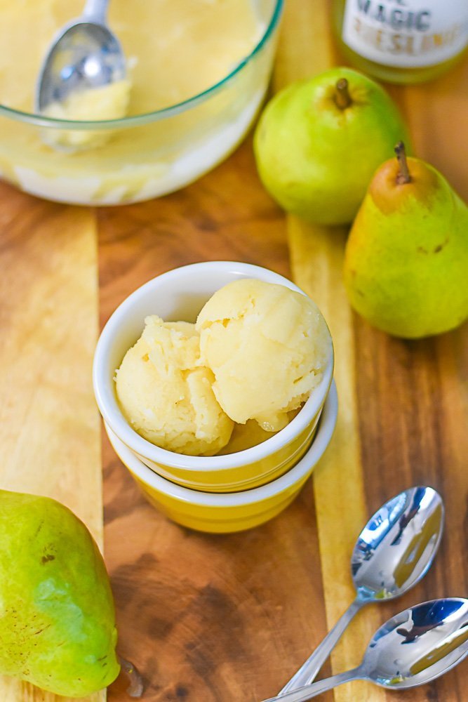 fruit and wine sorbet in small yellow bowls, surrounded by fresh pears and two spoons