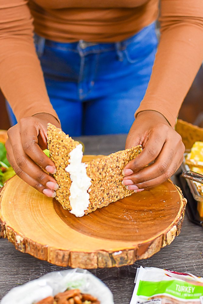 hands securing two pieces of crispbread together with cream cheese