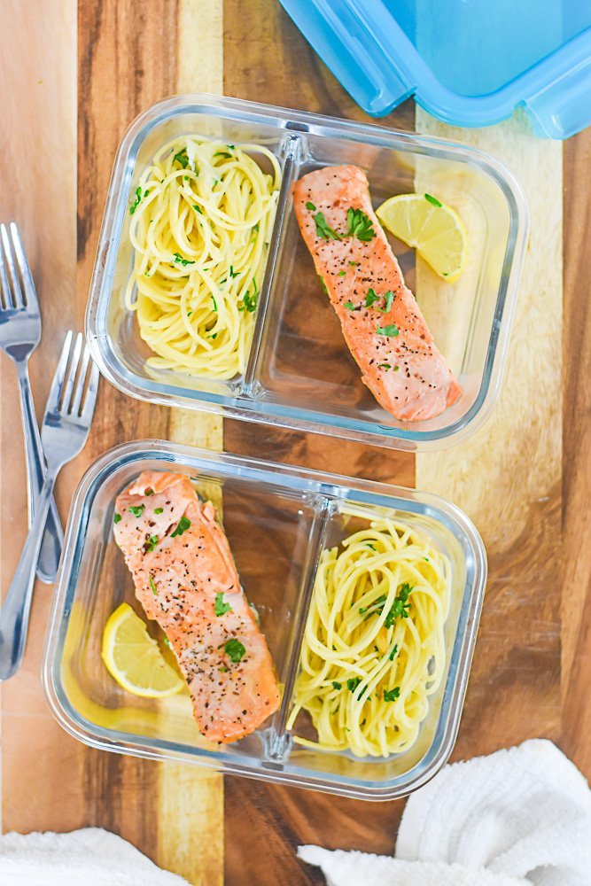 portions of seared salmon and pasta with parsley in divided glass meal prep containers