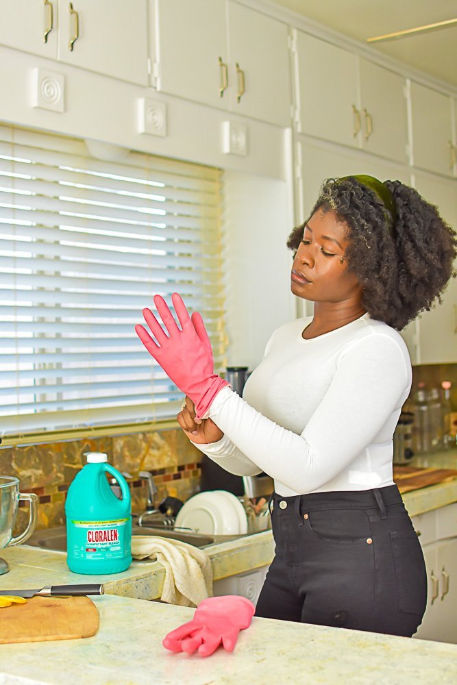 Jazzmine putting on pink rubber glove in kitchen.