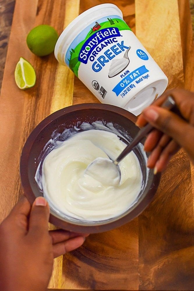 mixing Greek yogurt and fresh lime juice in wooden bowl.