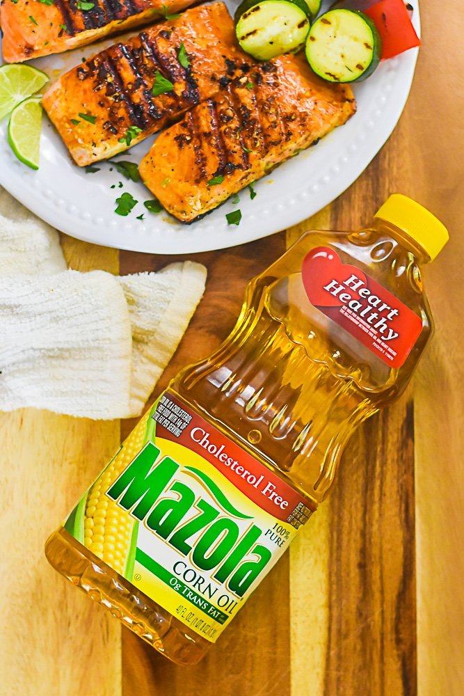 bottle of Mazola Corn Oil laying next to platter of grilled salmon filets.