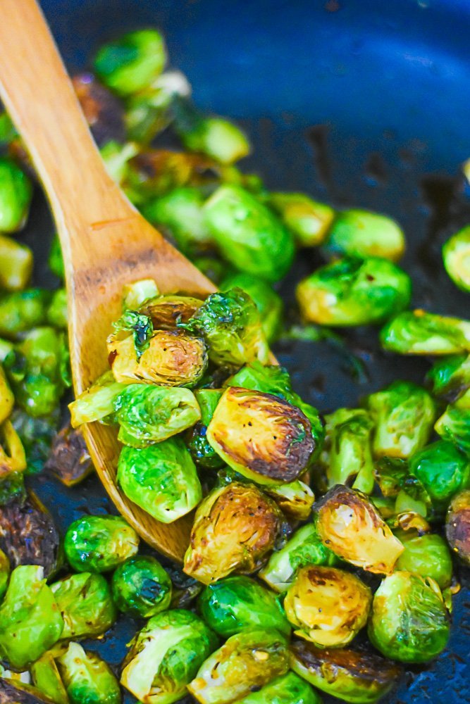 sautéed brussels sprouts in pan on wooden spoon.