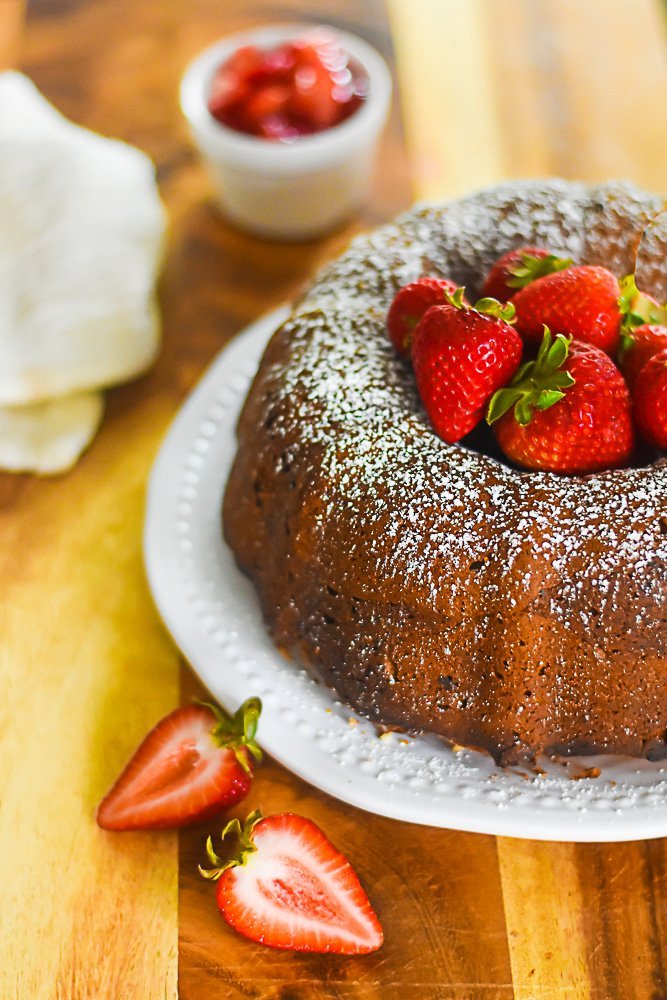 baked sour cream strawberry pound cake decorated with powdered sugar and pile of fresh strawberries.