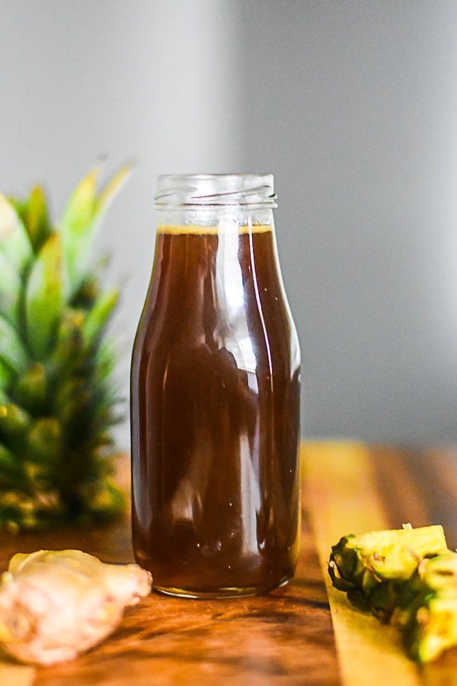glass bottle of homemade brown sugar simple syrup infused with pineapple and ginger.