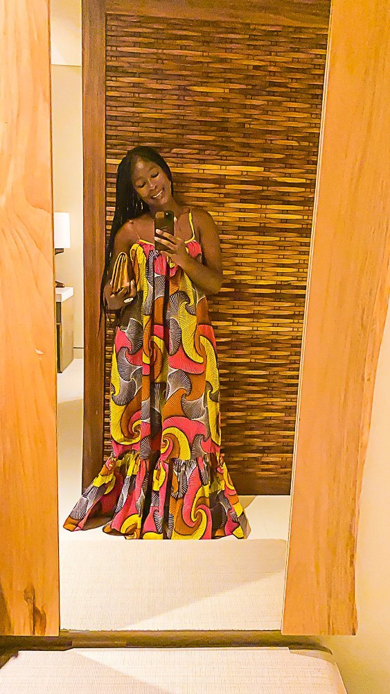 Jazzmine wearing colorful African-print maxi dress taking mirror selfie.