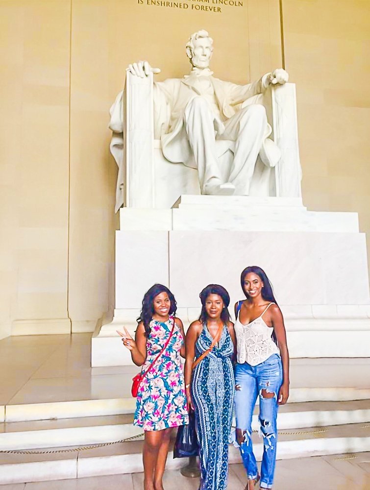 three Black women standing in front of Lincoln Memorial statue in Washington DC.