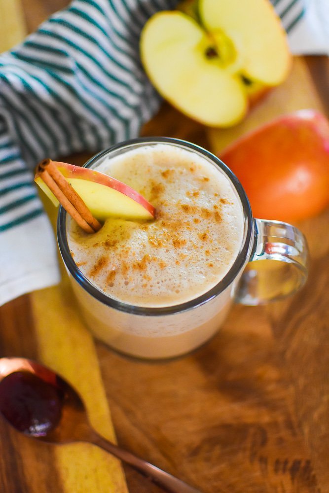 fancy homemade apple chai latte garnished with apple slice and cinnamon stick.