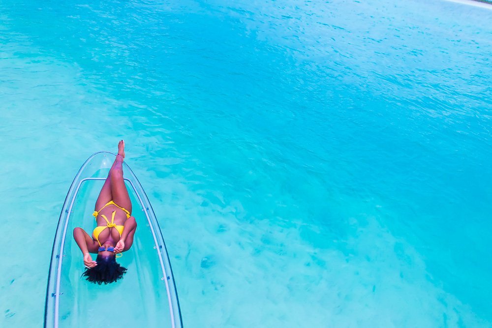 Jazzmine laying on clear kayak in water at Grace Bay Beach.