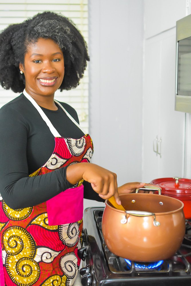 Jazzmine stirring pot of red stew and smiling.