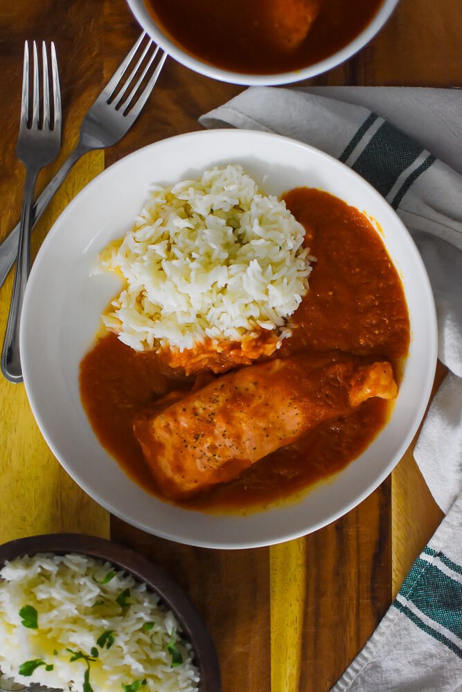 Nigerian red stew, roasted salmon, and white rice plated.