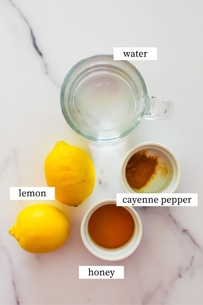 honey, lemon, water, and cayenne pepper on marble countertop.