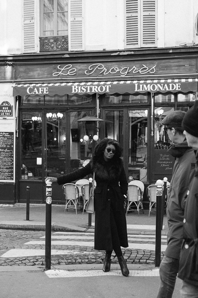 Jazzmine posing in front of Montmartre cafe as two passersby stare.