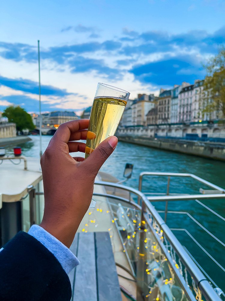 Holding up flute of champagne on Seine River cruise.