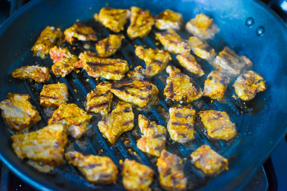 marinated suya beef cooking on grill pan.