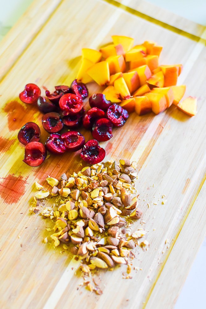 chopped peach, cherries, and almonds on wood cutting board.