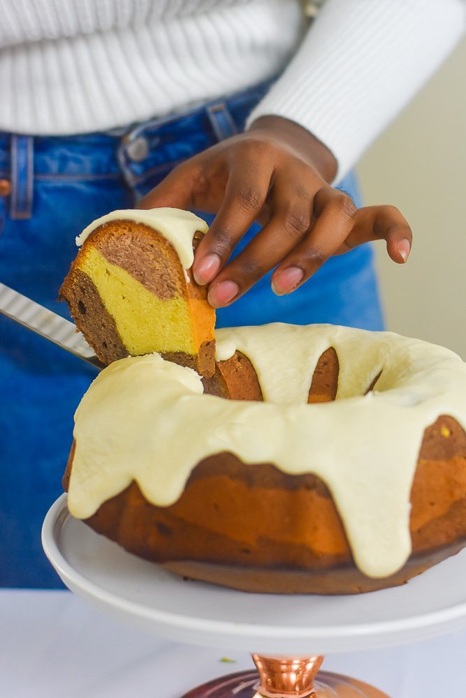 Lifting slice of three flavor pound cake off cake stand.