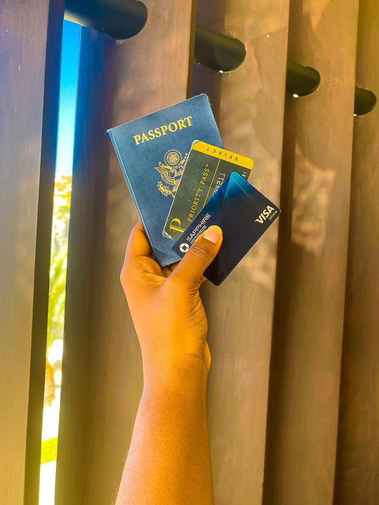 holding passport, Priority Pass card, and Chase Sapphire Reserve credit card.