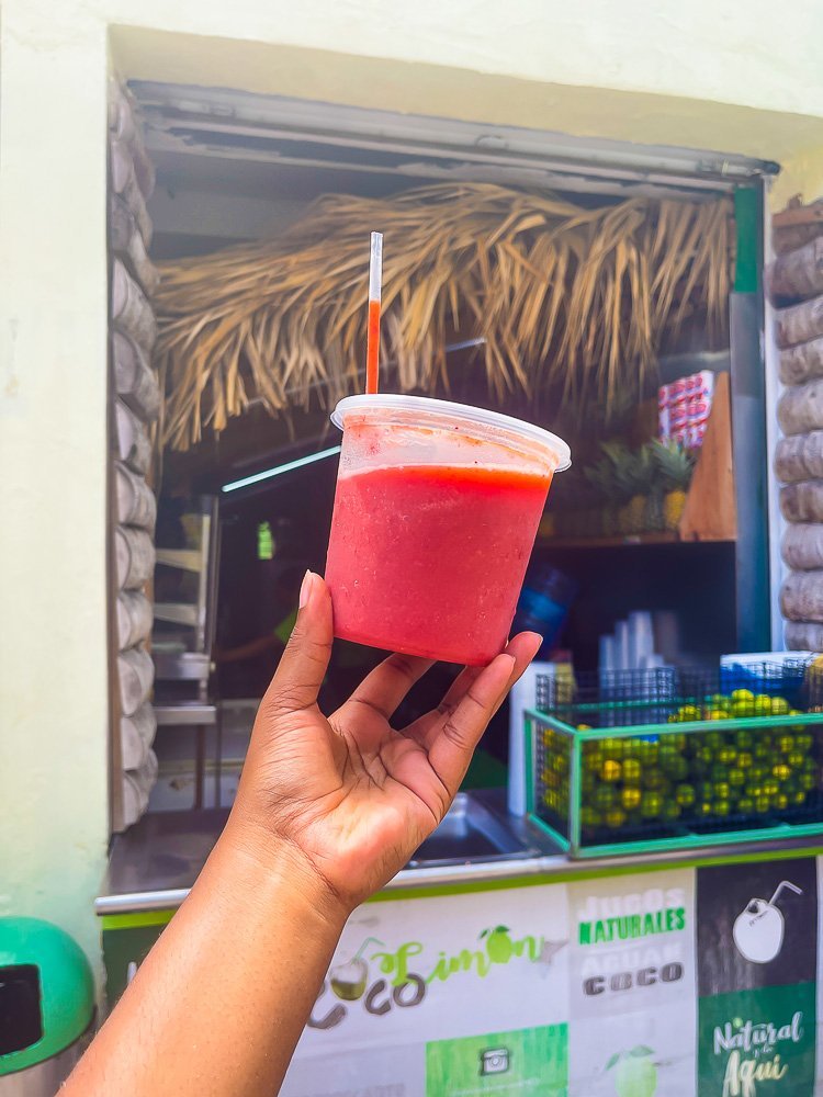 holding container of fresh strawberry tamarind juice.