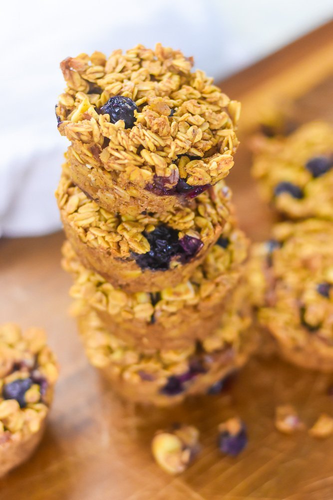 golden baked oatmeal cups on cutting board with almonds and blueberries.