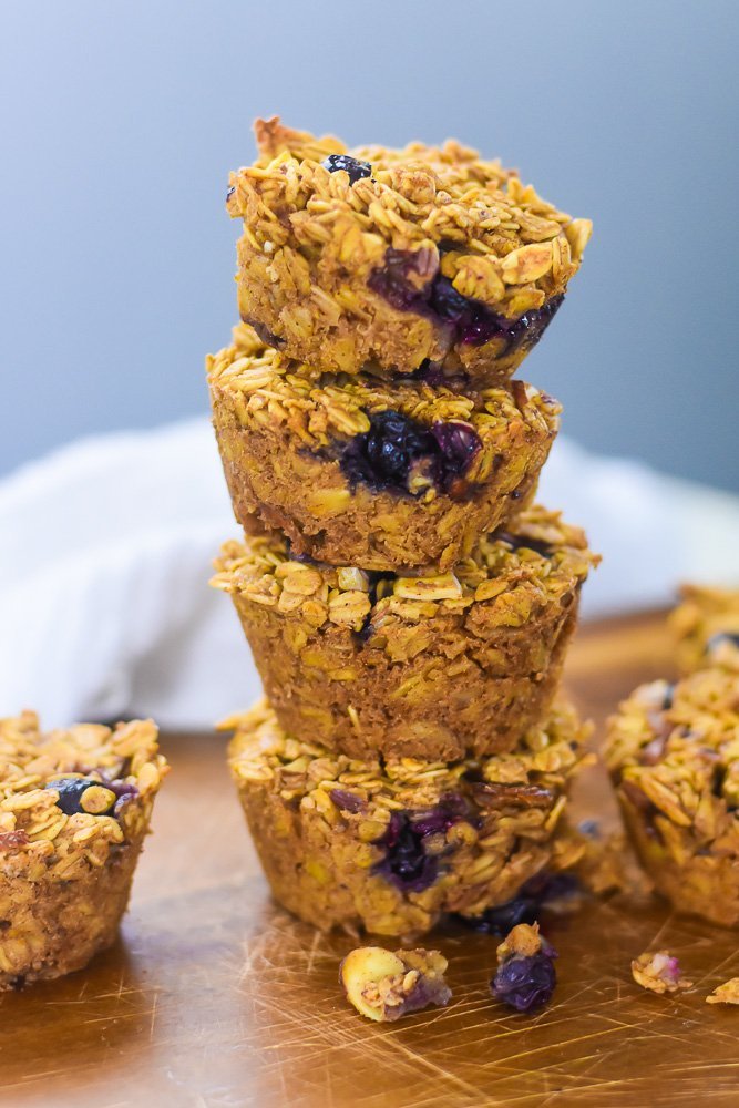 four blueberry baked oatmeal cups stacked on cutting board.