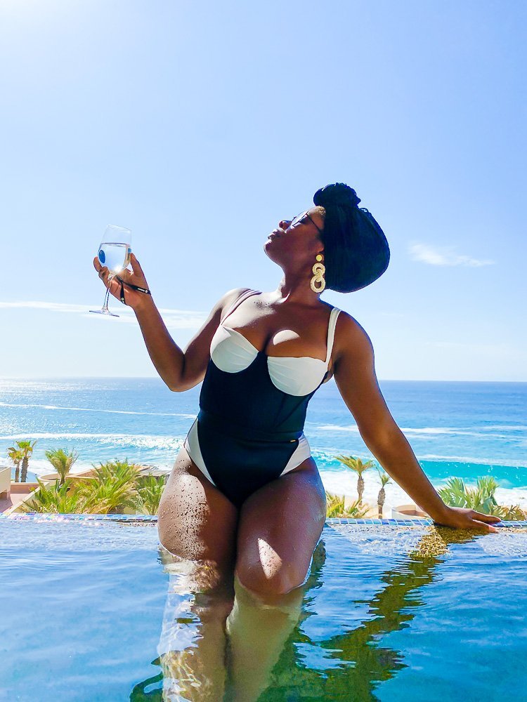wearing black and white Marcia B Maxwell corset swimsuit in infinity pool.