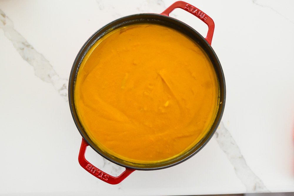 red Staub Dutch oven filled with creamy sweet potato soup.