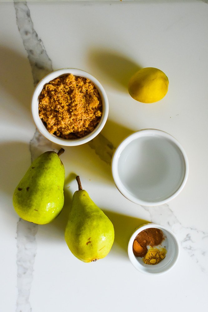 brown sugar, cinnamon, nutmeg, lemon, pears, and water on white granite counter top.