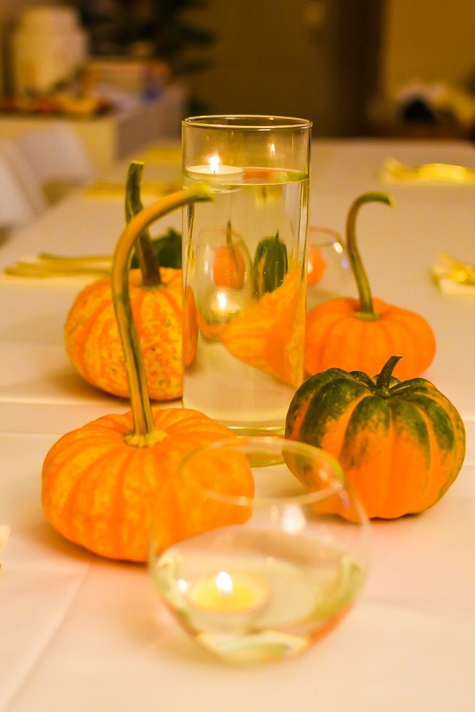 Friendsgiving tablescape with mini gourds and floating candles.