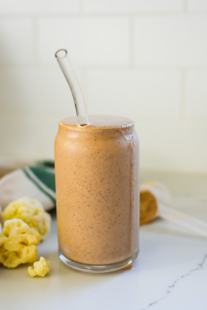 blended chocolate smoothie with visible bits of ground chia seeds  in tall glass .