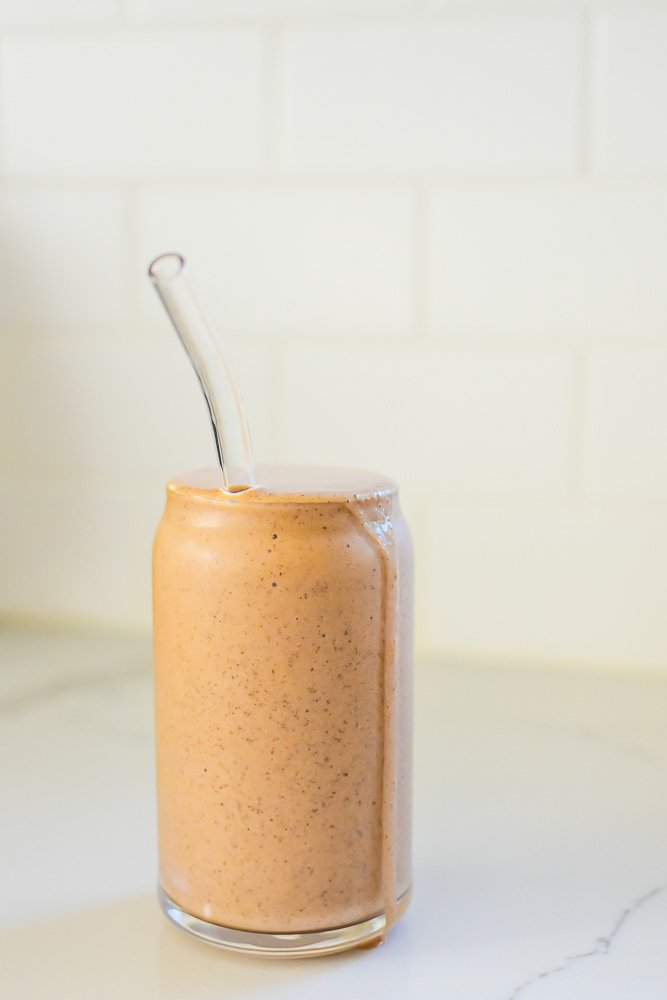 beer can glass filled with a chocolate smoothie and glass straw.
