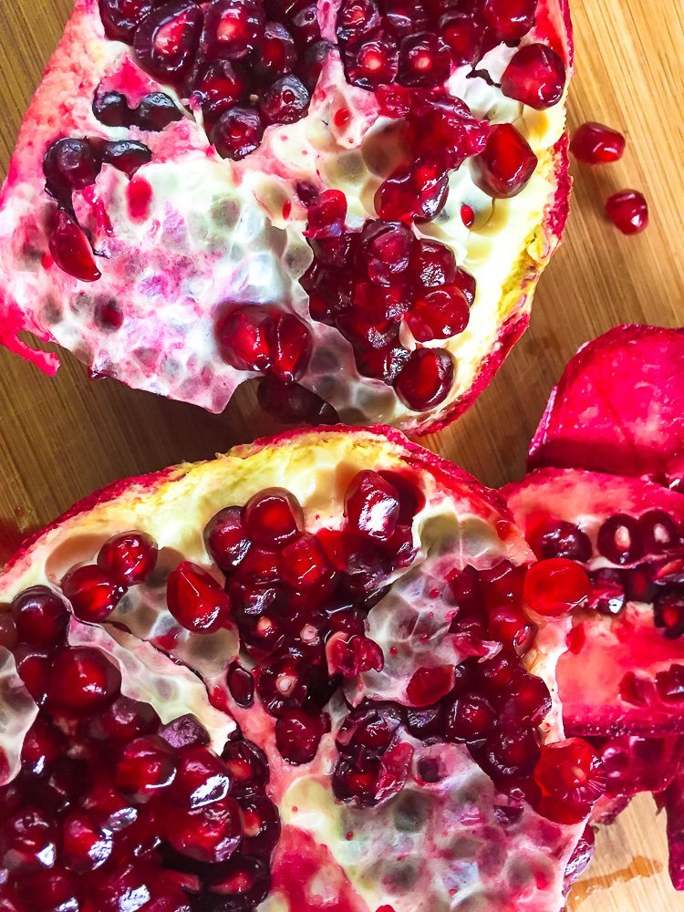 open pomegranate fruit on wooden cutting board.