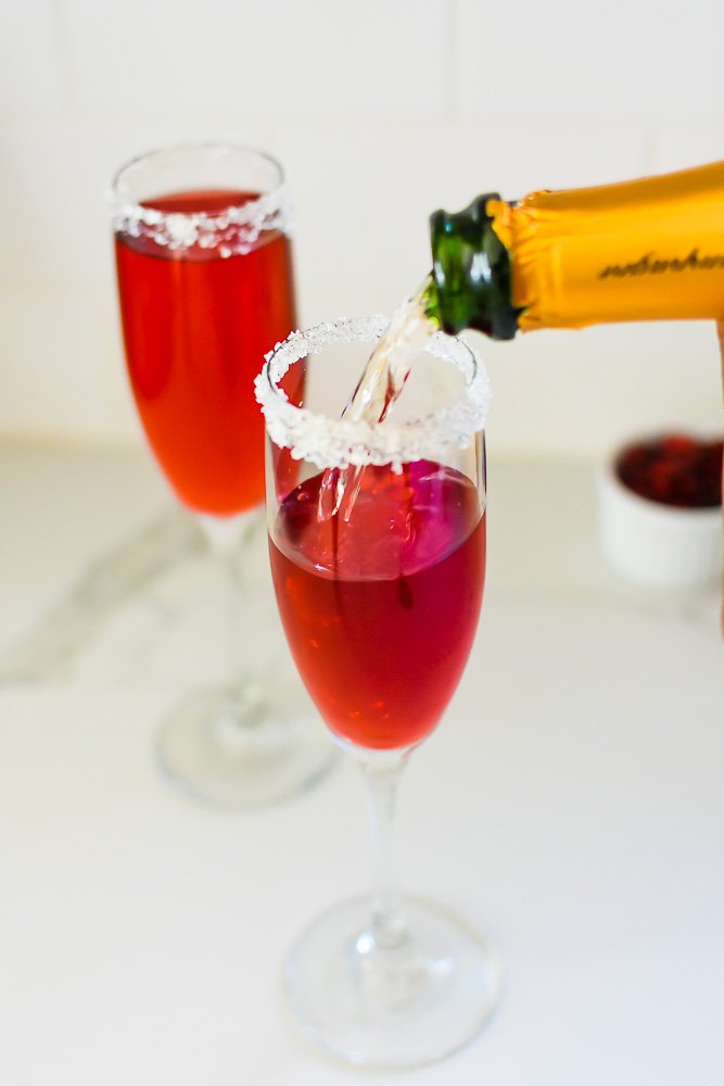 pouring champagne into flute with pomegranate juice.