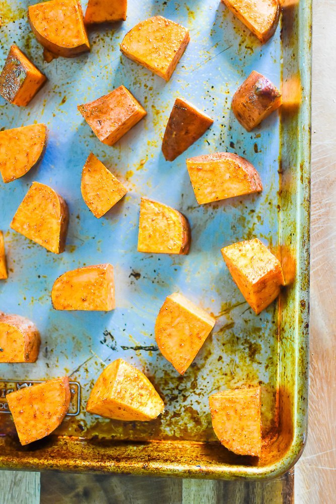 sweet potato cubes prepared for roasting on metal sheet pan.