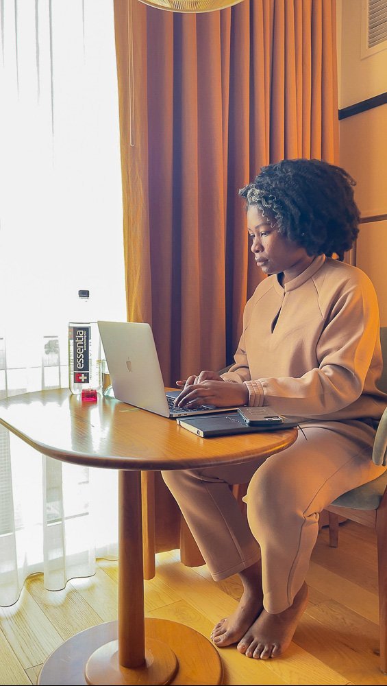 Jazzmine working on a laptop at wooden table in Eaton DC hotel room.