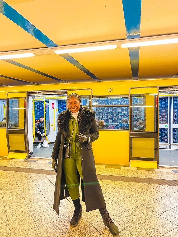 Jazzmine posing in front of yellow subway car at Berlin transit station.