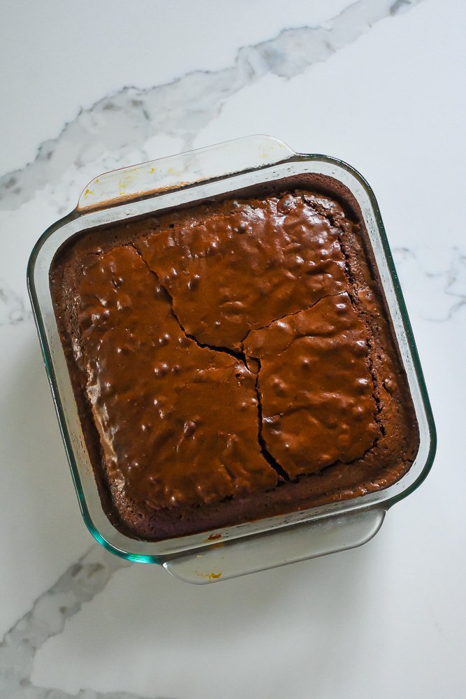 baked brownie in square glass pan.