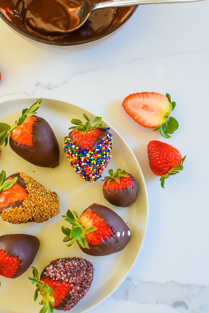 white round platter of colorfully decorated chocolate dipped berries.
