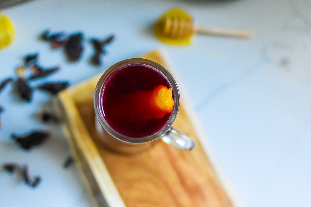 hot toddy made with hibiscus tea with stripe of lemon peel floating on top.