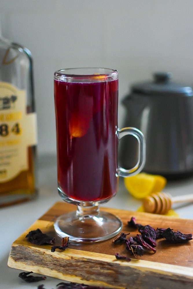 hot toddy in clear glass mug with hibiscus tea and Uncle Nearest 1884 whiskey.