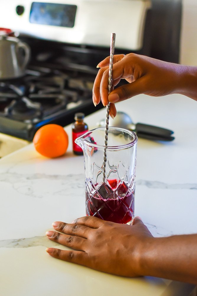 mixing hibiscus tea and honey in a mixing glass with bar spoon.
