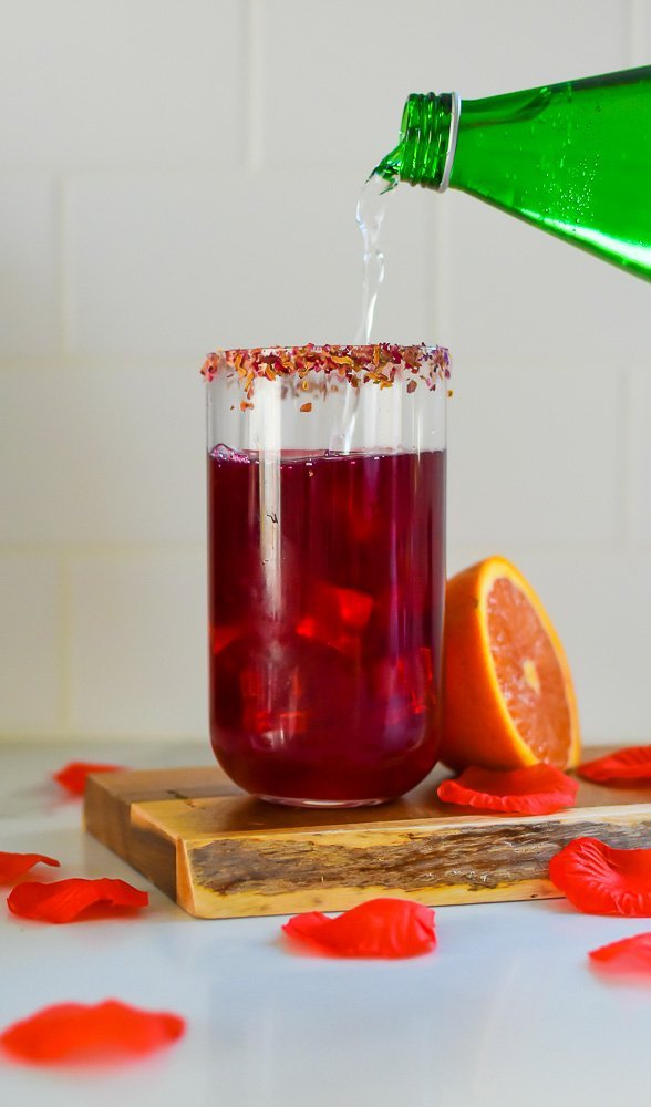 pouring sparkling water into hibiscus tea drink.