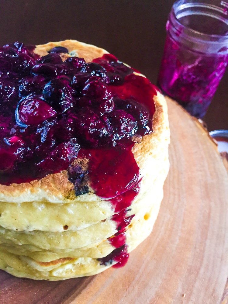 blueberry compote dripping down double stack of homemade blueberry pancakes.