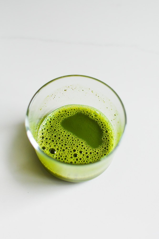 matcha dissolved in hot water in small glass.