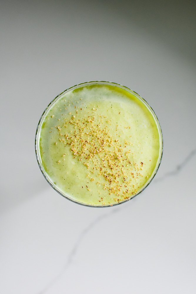 creamy top layer of matcha martini with pieces of fresh nutmeg floating on top.