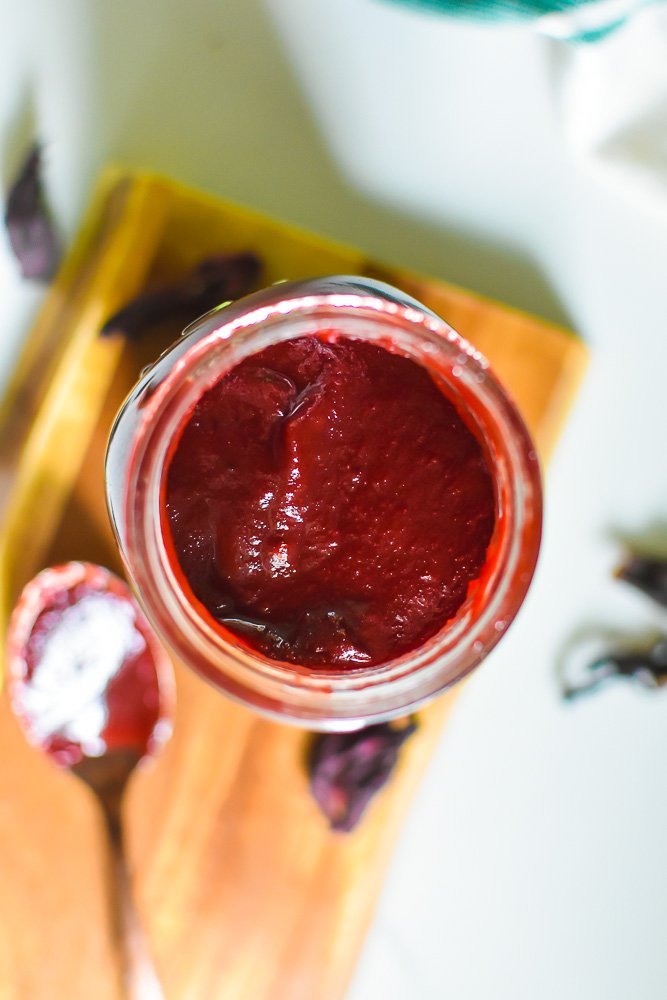 thick hibiscus BBQ sauce in mason jar surrounded by dried hibiscus flowers.