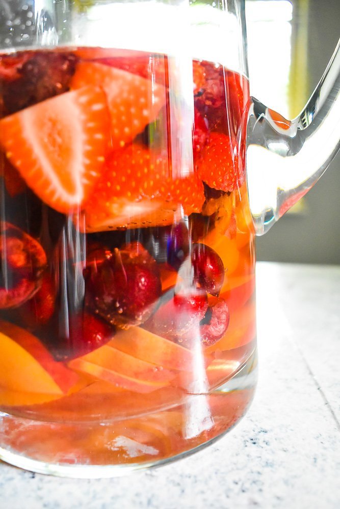 glass pitcher of pink sangria with fresh fruits soaking inside.